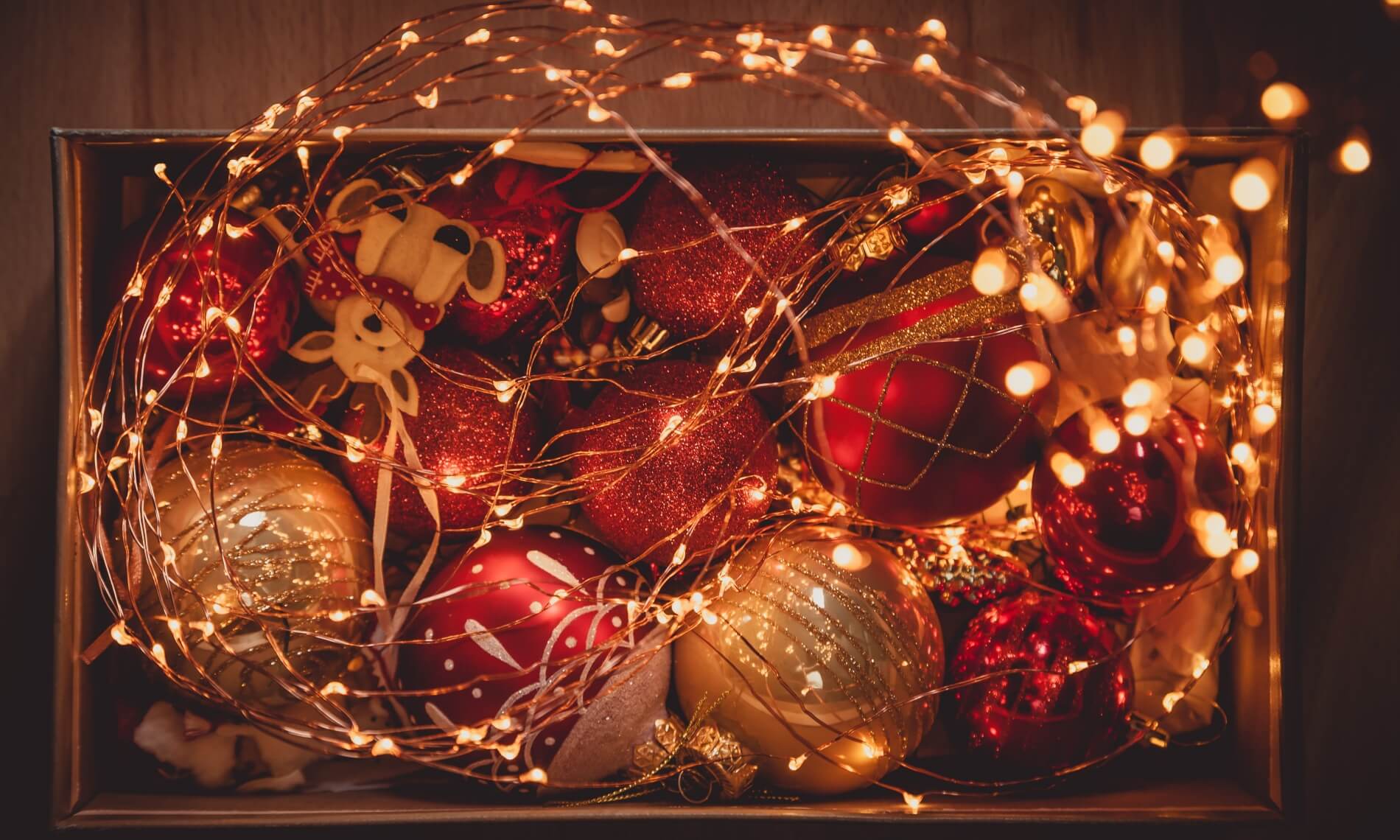 Lit up yellow Christmas lights with red and gold bauble balls in a box