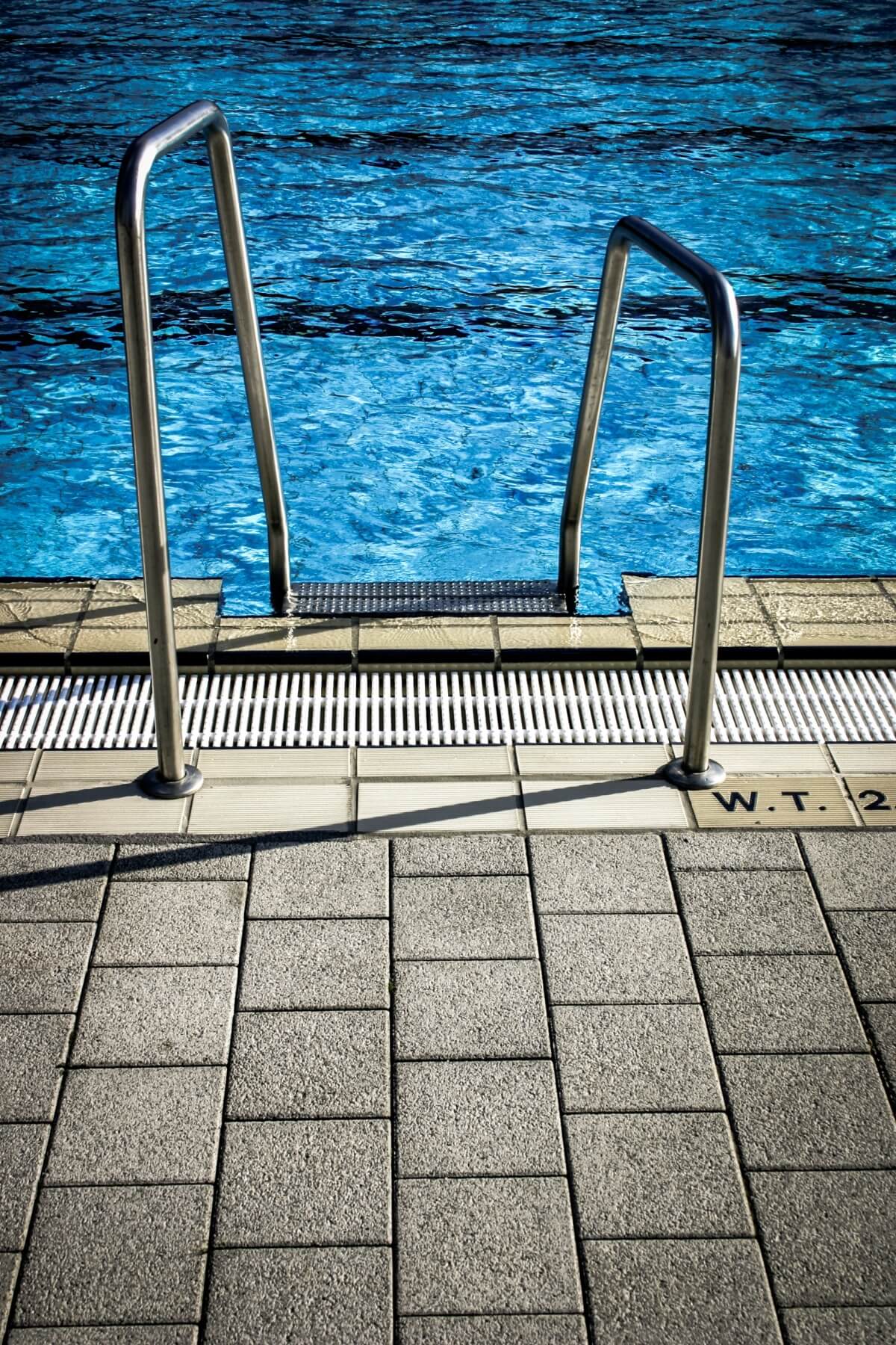 View of a swimming pool steps with assistance bars